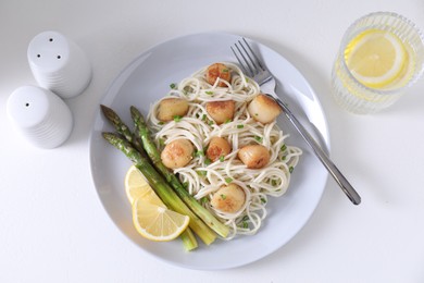 Photo of Delicious scallop pasta with asparagus, green onion and lemon served on white table, flat lay