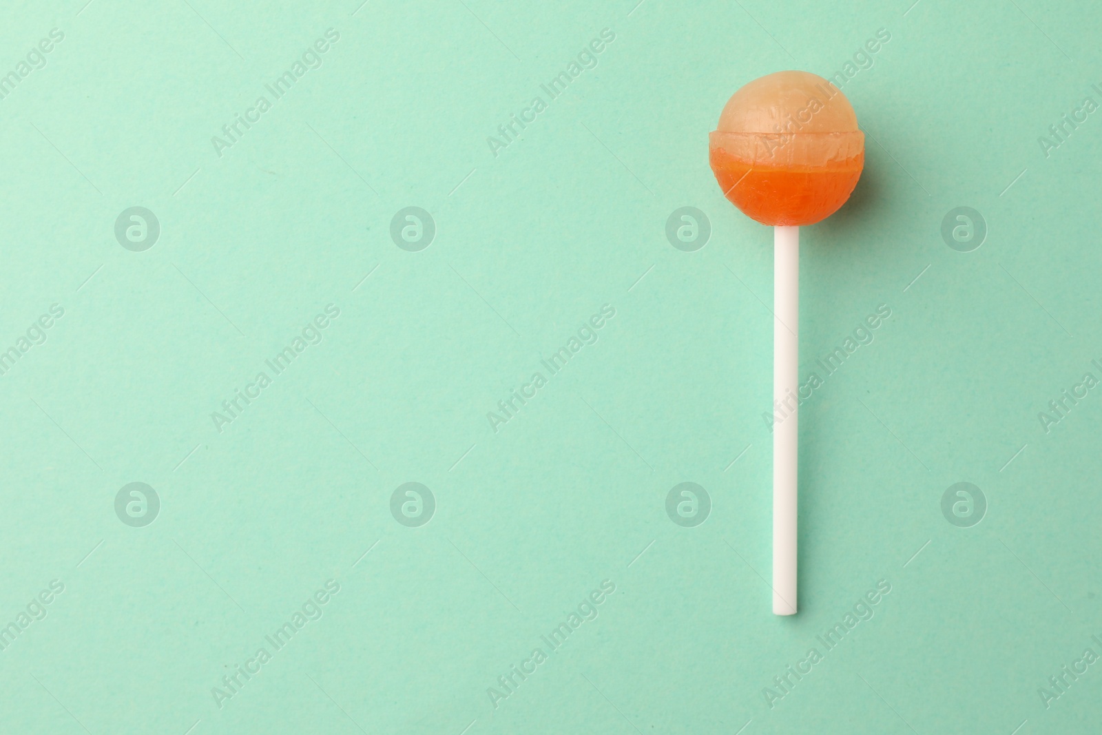 Photo of Tasty lollipop on turquoise background, top view. Space for text