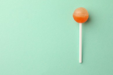 Photo of Tasty lollipop on turquoise background, top view. Space for text