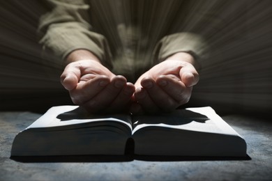 Religion. Christian man praying over Bible at table, closeup