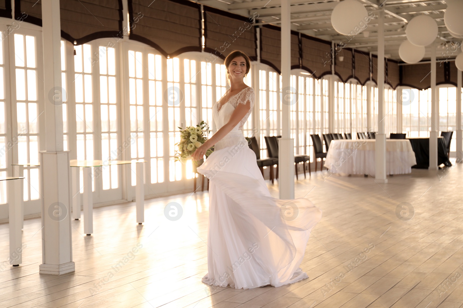 Photo of Gorgeous bride in beautiful wedding dress with bouquet in restaurant