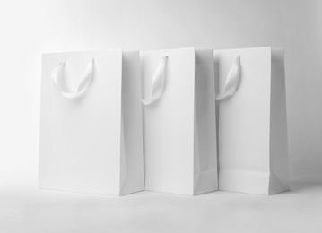 Photo of Paper shopping bags with ribbon handles on white background. Mockup for design