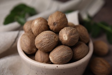 Photo of Whole nutmegs in bowl on table, closeup