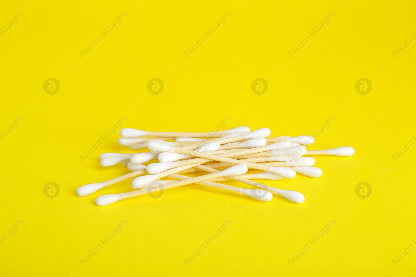 Photo of Many wooden cotton buds on yellow background