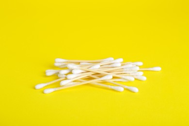 Many wooden cotton buds on yellow background