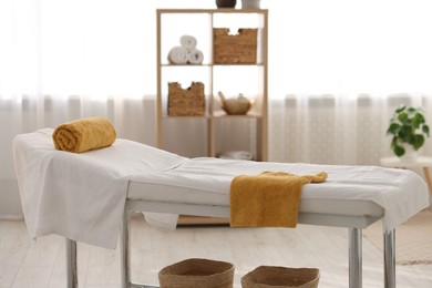 Comfortable massage table with clean towels in spa center