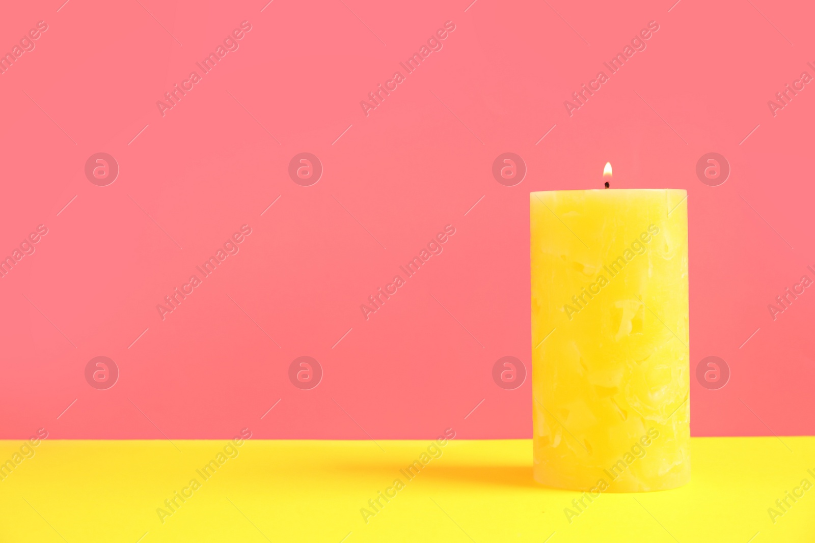 Photo of Alight wax candle on color background. Space for text