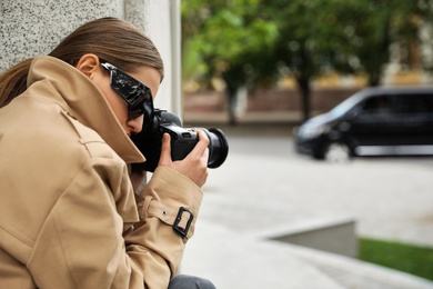 Photo of Private detective with modern camera spying on city street