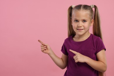 Photo of Special promotion. Little girl pointing at something on pink background. Space for text