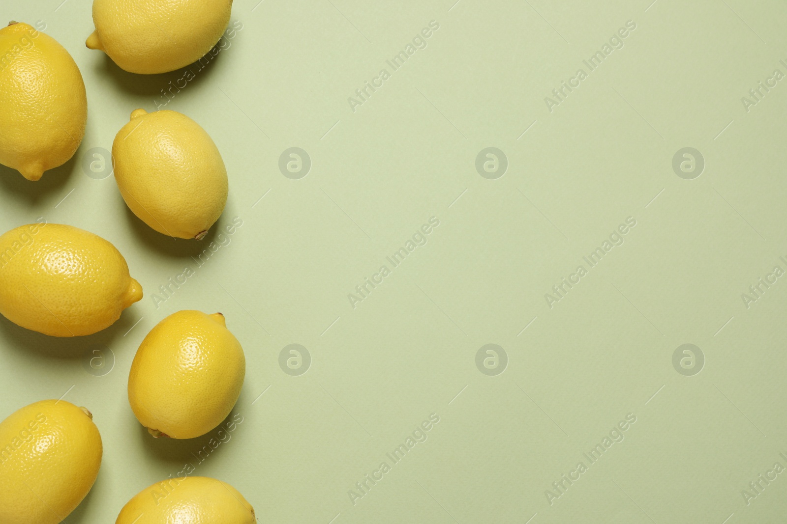 Photo of Fresh ripe lemons on light green background, flat lay with space for text