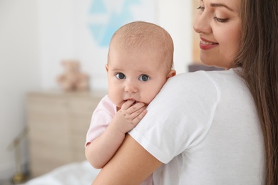 Photo of Mother holding her adorable baby at home. Space for text