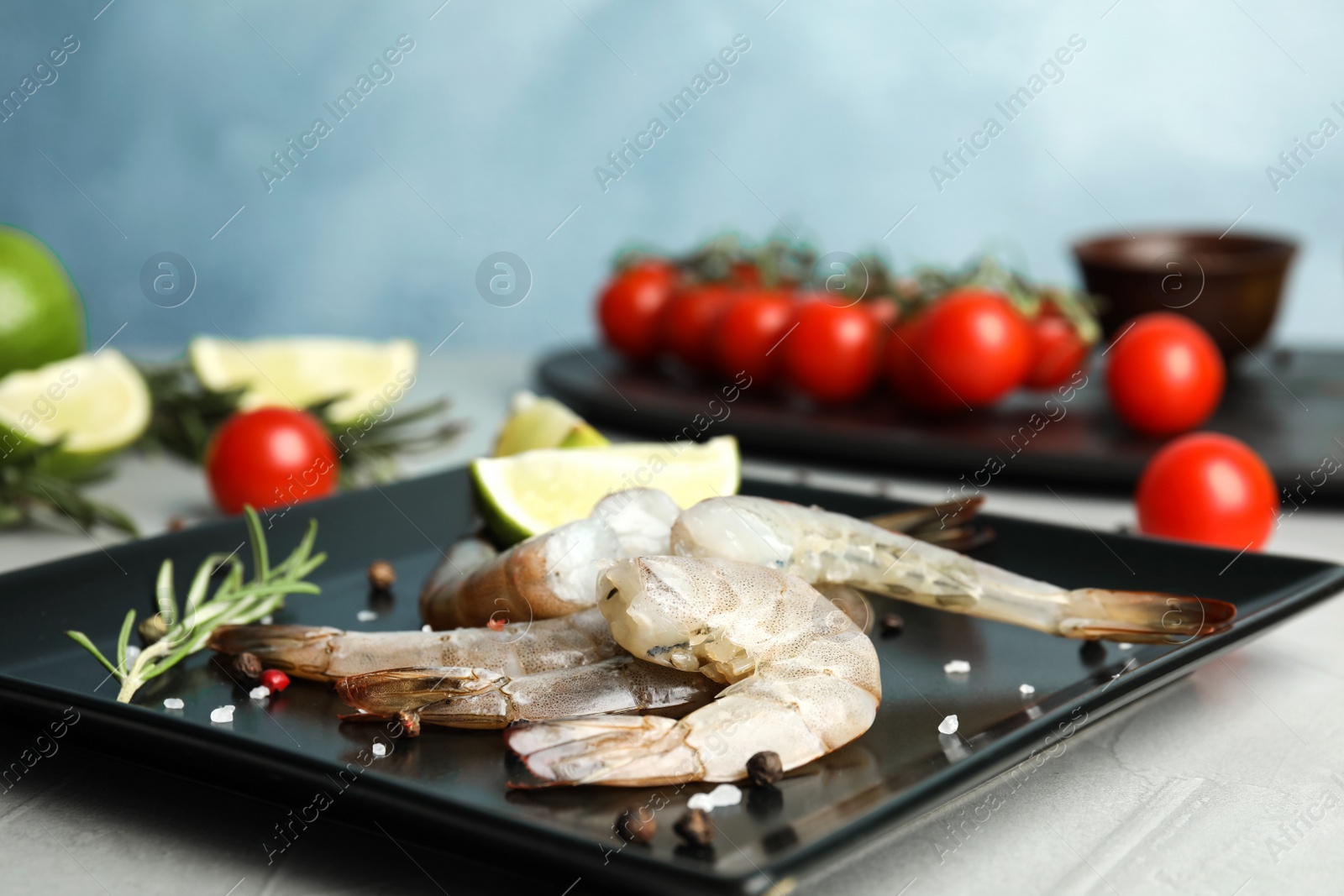 Photo of Fresh raw shrimps with lime and rosemary on plate, closeup