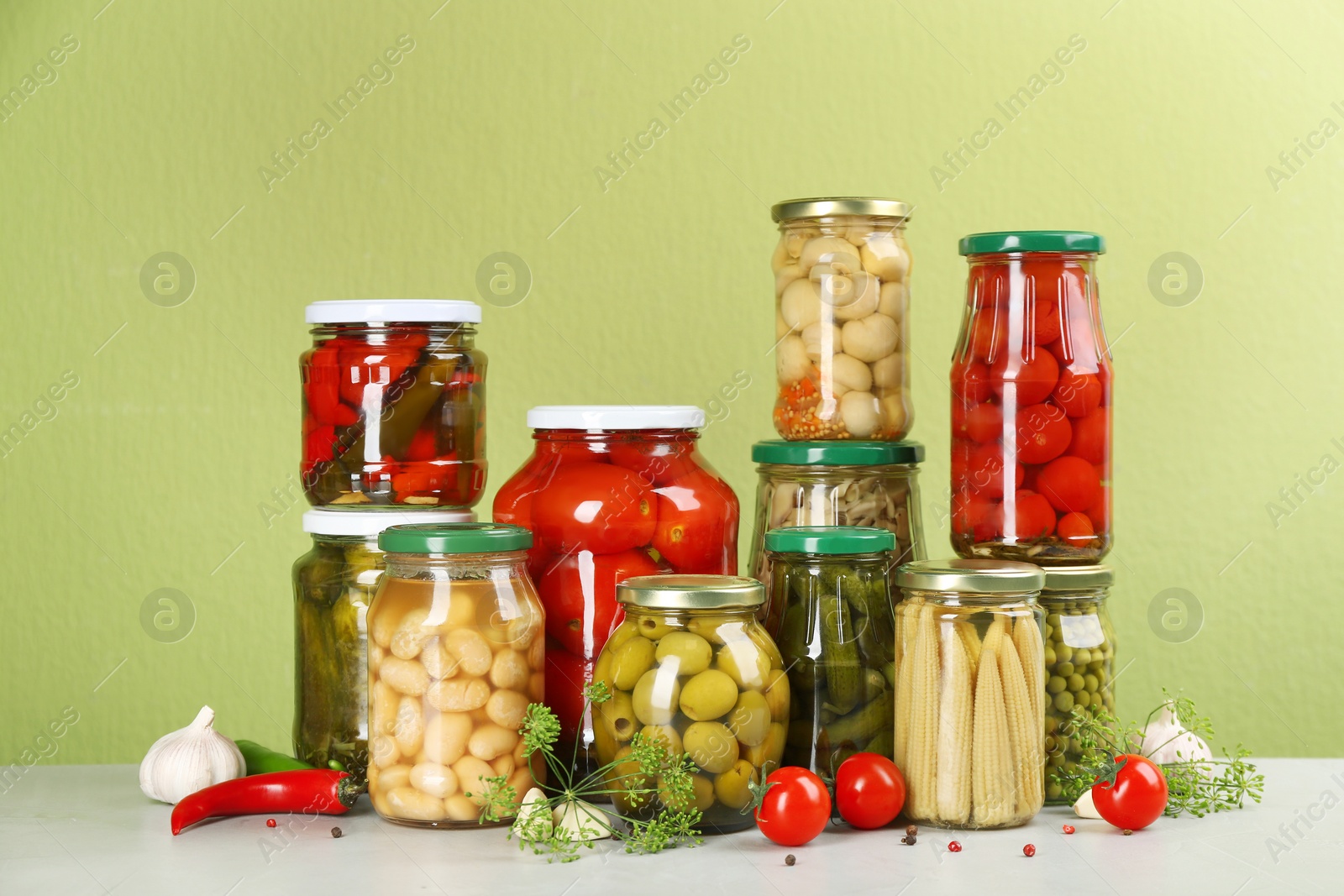 Photo of Jars of pickled vegetables and ingredients on light table