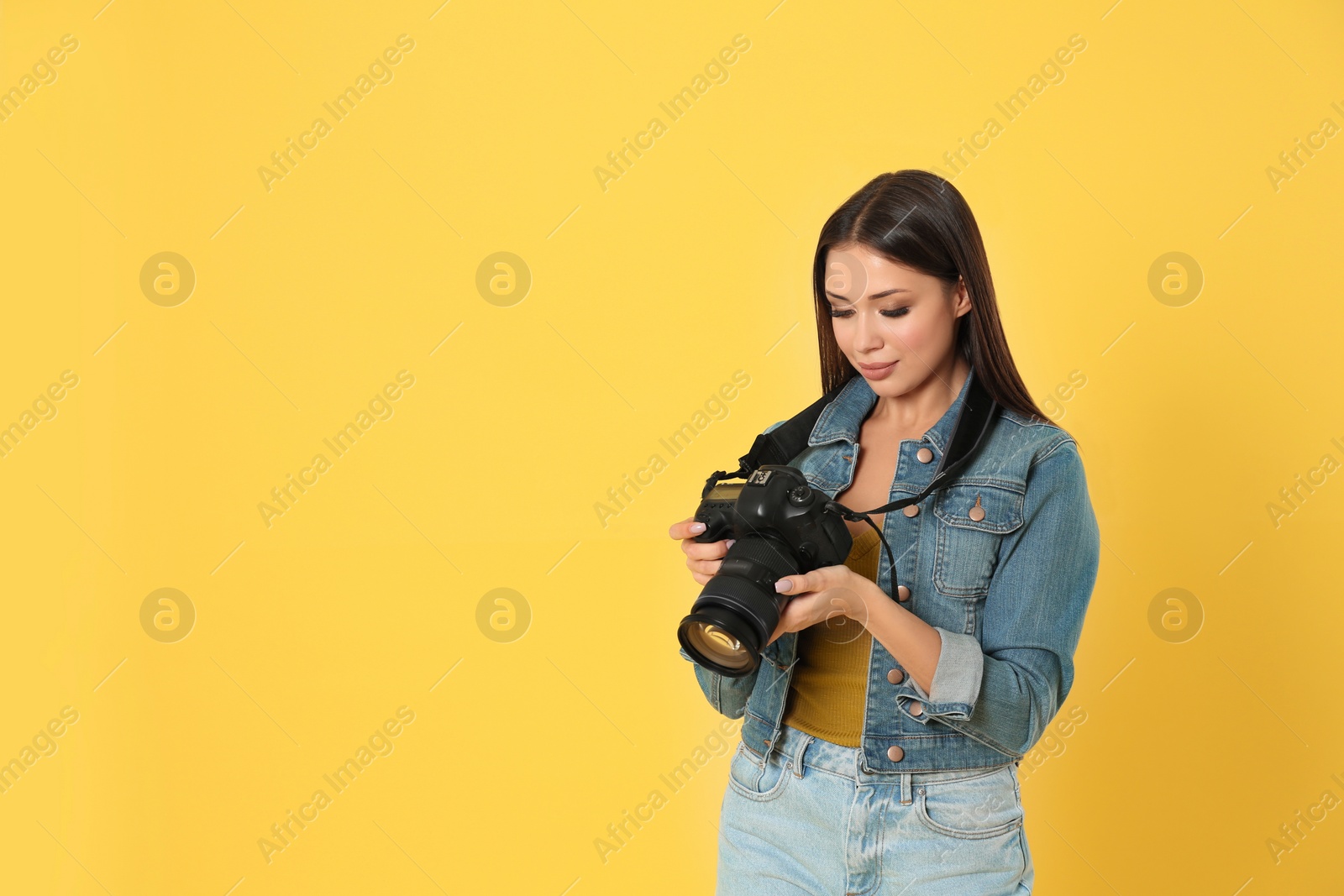 Photo of Professional photographer working on yellow background in studio. Space for text