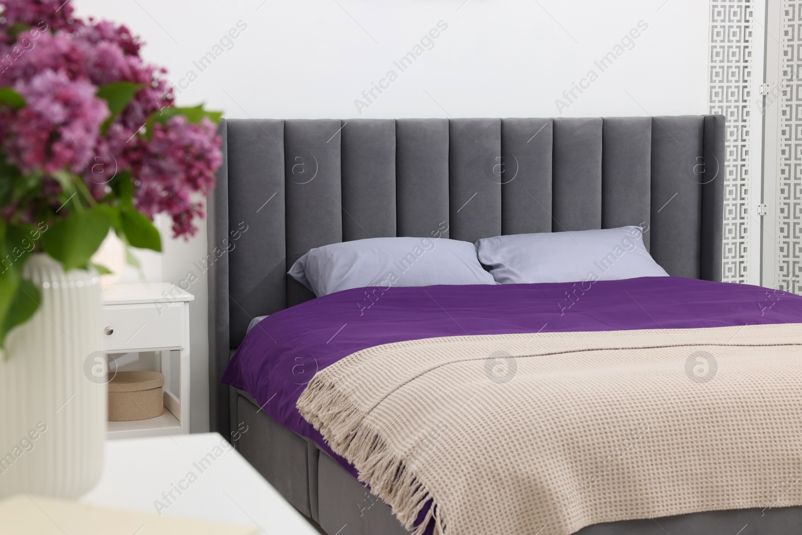 Photo of Comfortable bed with purple linens in bedroom. Interior design