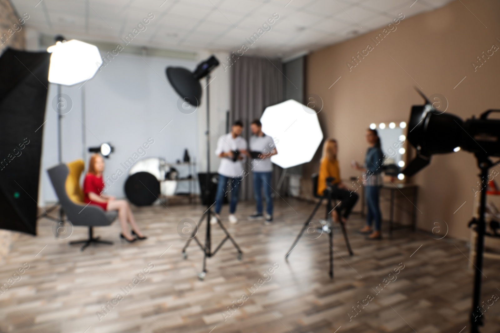 Photo of Blurred photo studio with professional equipment and team of workers