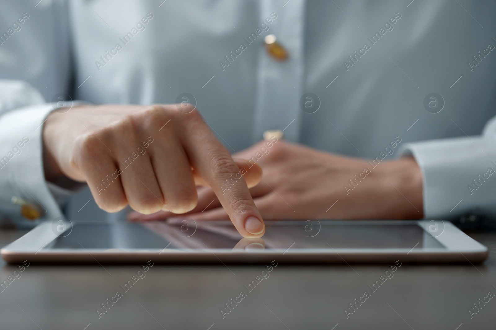 Photo of Closeup view of woman using modern tablet at table