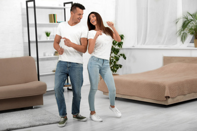 Happy young couple dancing together at home