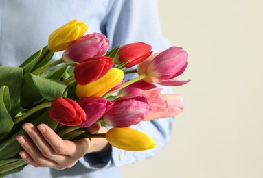 Woman holding beautiful colorful tulip flowers on white background, closeup. Space for text