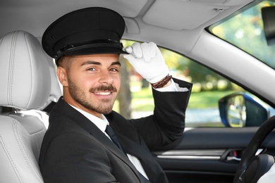 Photo of Young handsome driver in luxury car. Chauffeur service