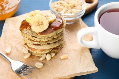 Photo of Banana pancakes with jam served on blue wooden table, closeup