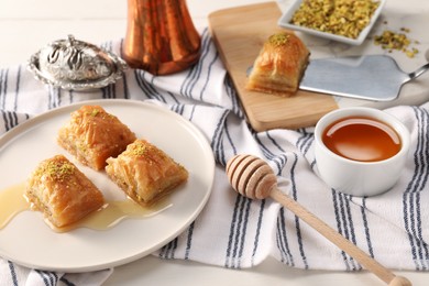 Photo of Delicious sweet baklava with pistachios and honey on table