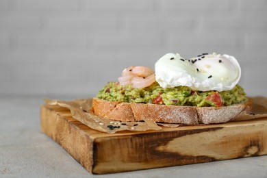 Delicious sandwich with guacamole, shrimps and fried egg on light grey table, closeup