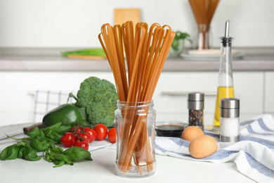 Photo of Uncooked buckwheat noodles and ingredients on white kitchen table