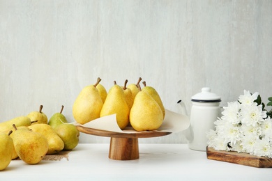 Photo of Stand with fresh ripe pears on table against light background