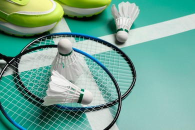 Photo of Feather badminton shuttlecocks, rackets and sneakers on court