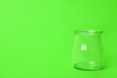 Open empty glass jar on light green background, space for text