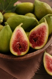 Photo of Cut and whole green figs in bowl on table, closeup