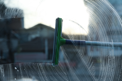 Cleaning window with squeegee indoors. Household chores