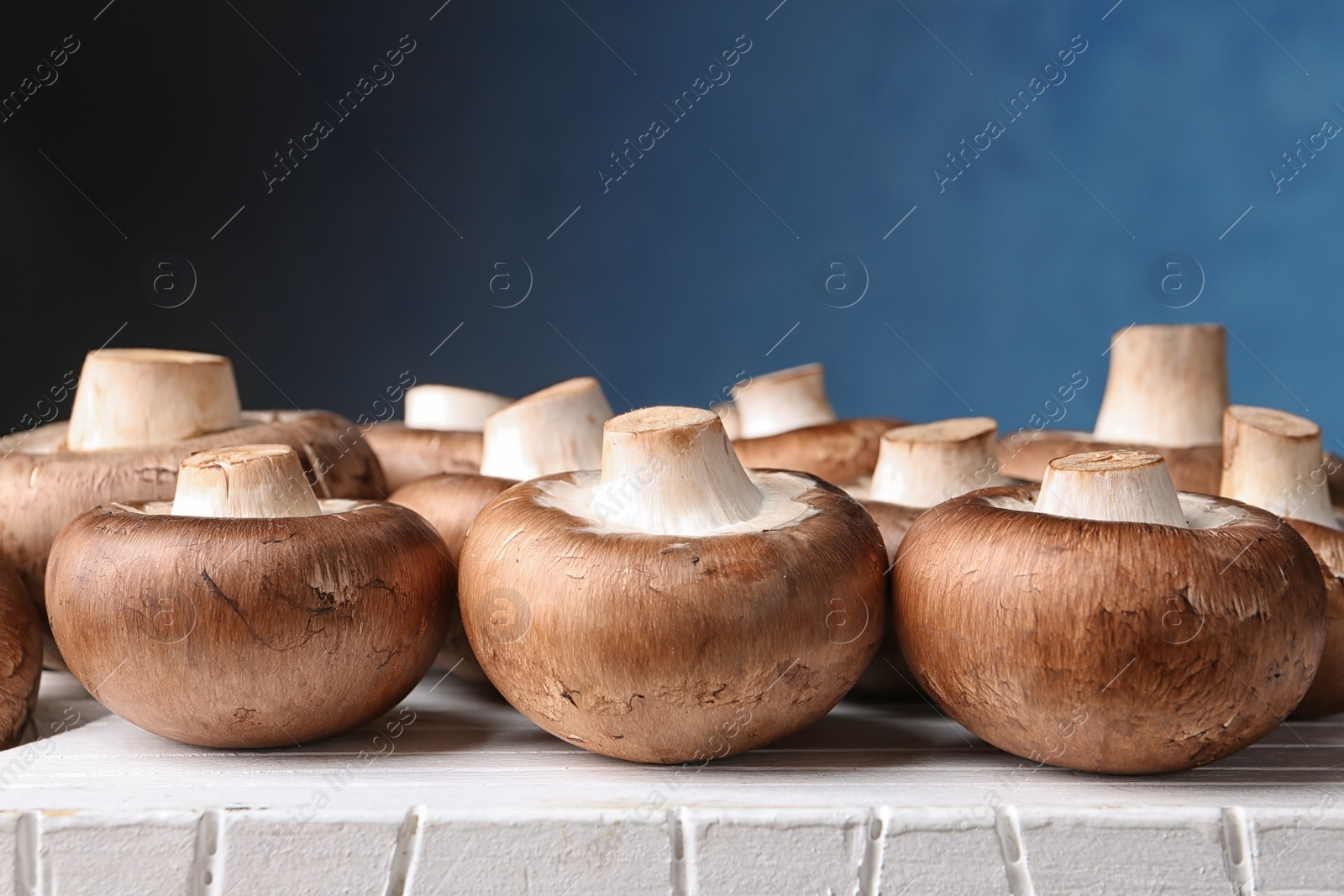 Photo of Fresh champignon mushrooms on board against color background, closeup. Space for text
