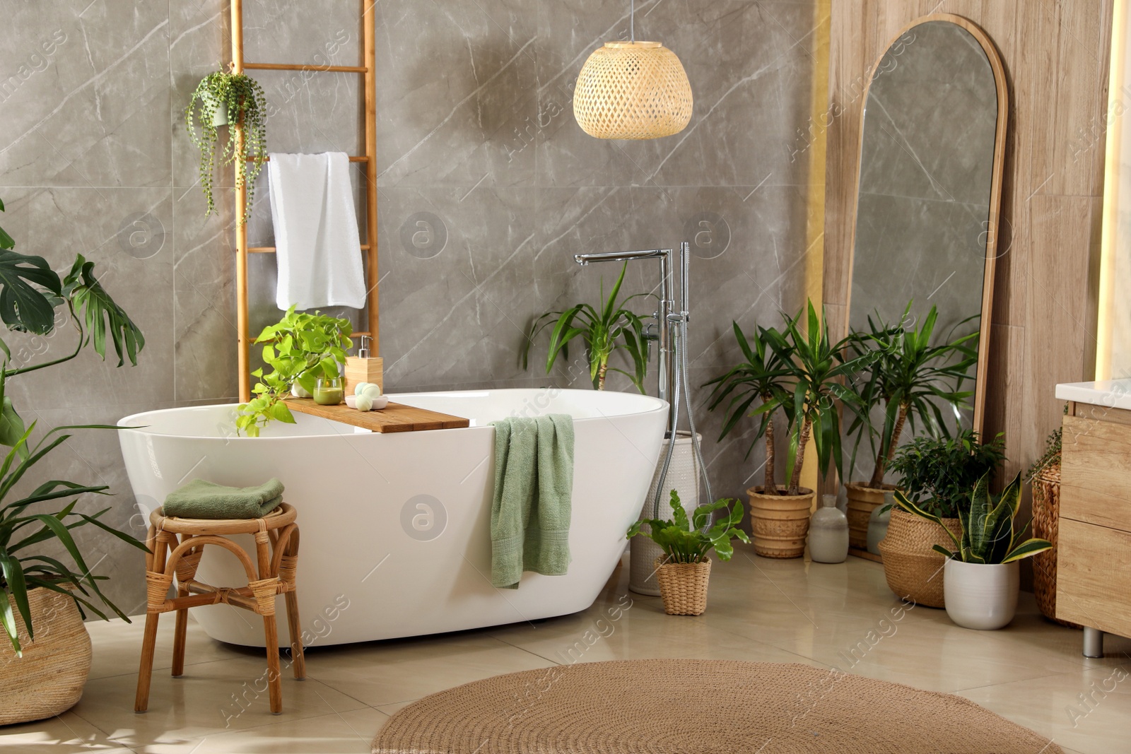 Photo of Modern white tub and beautiful green houseplants in bathroom. Interior design