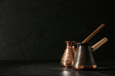 Photo of Beautiful copper turkish coffee pots on black table. Space for text