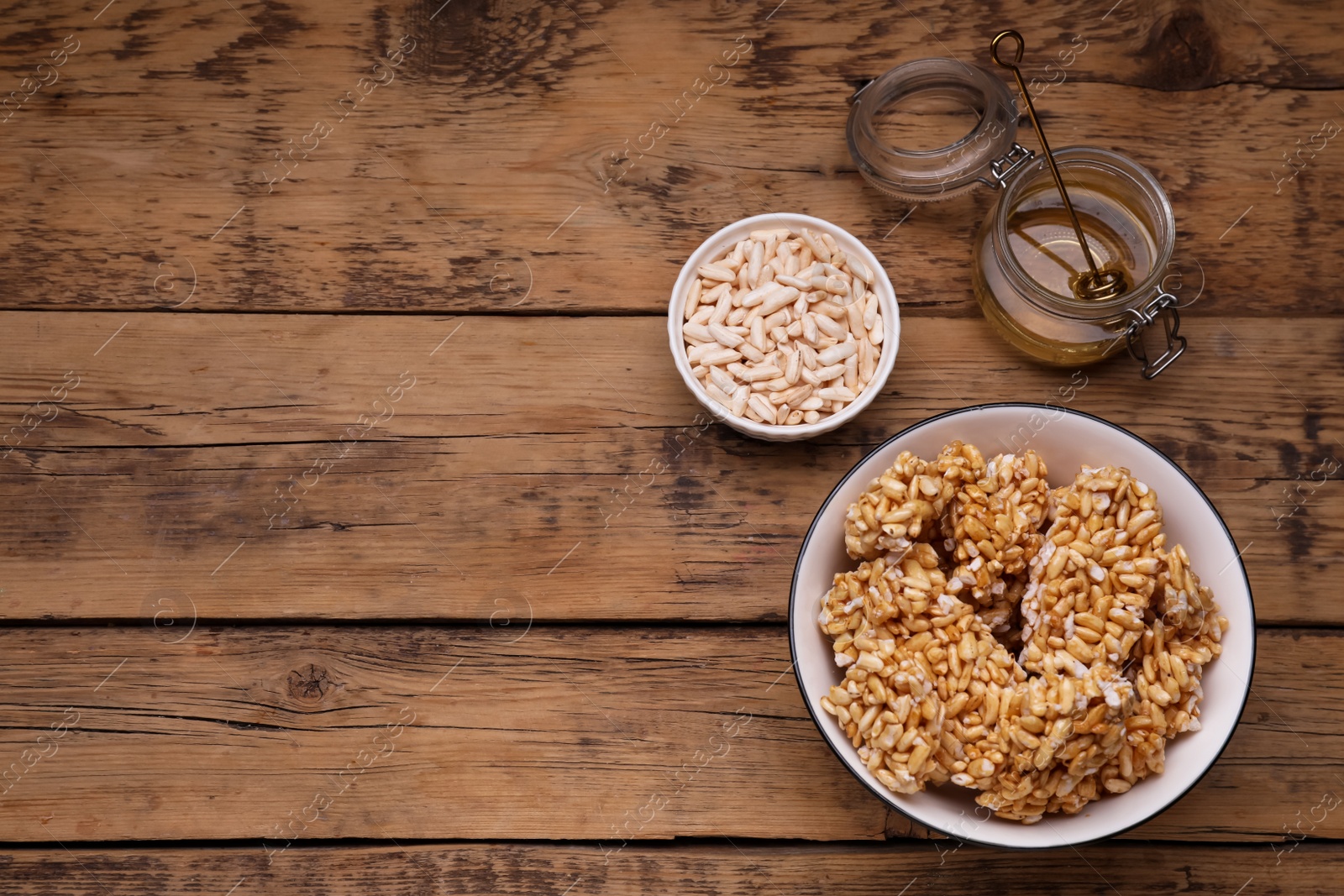 Photo of Puffed rice pieces (kozinaki) on wooden table, flat lay. Space for text