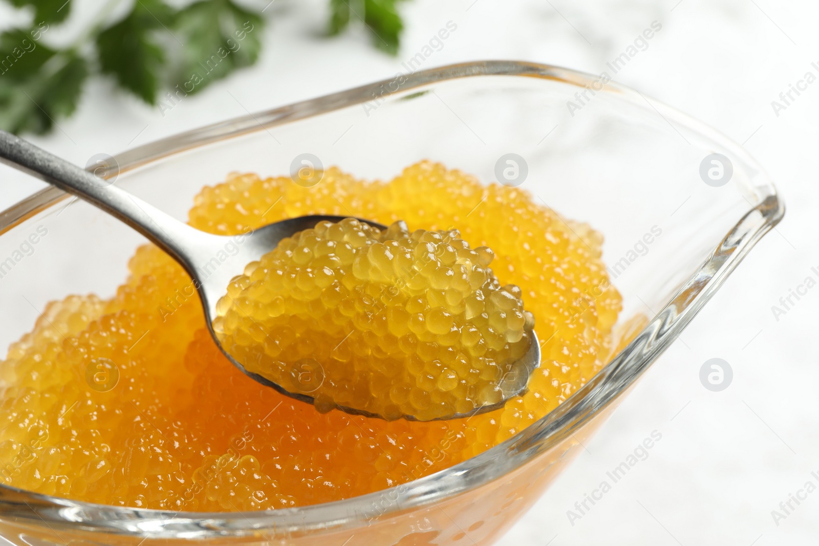 Photo of Fresh pike caviar in gravy boat and spoon on table, closeup