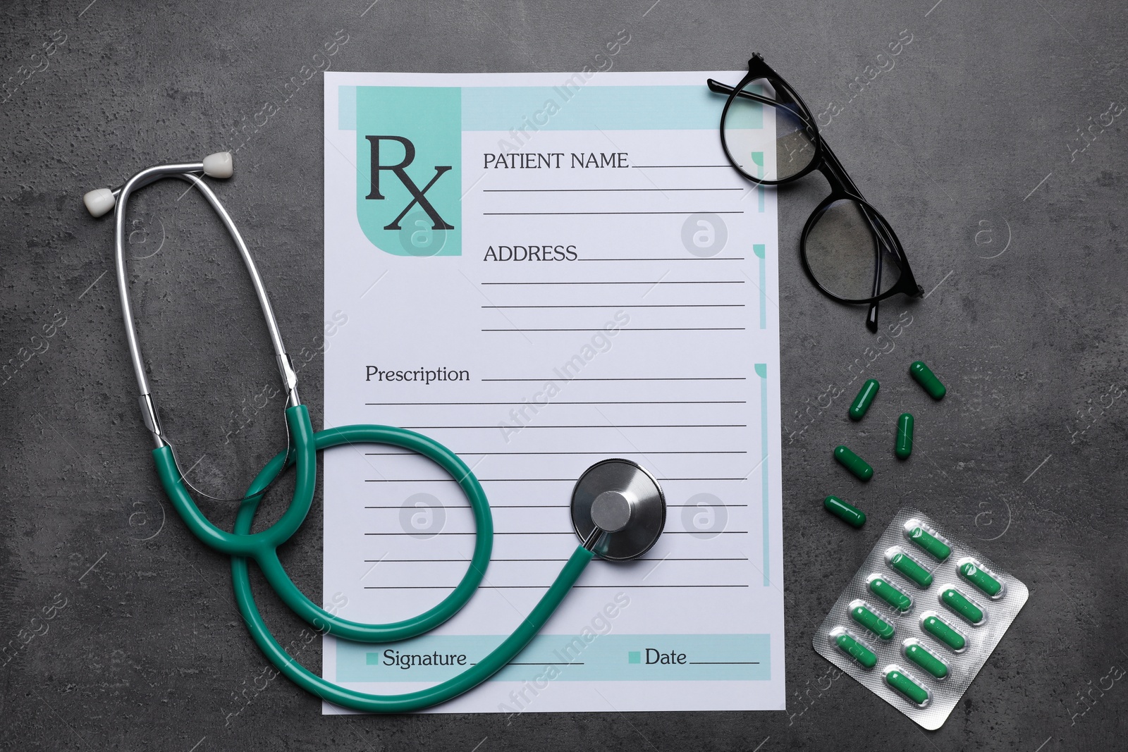 Photo of Medical prescription form, stethoscope, pills and glasses on dark grey table, flat lay