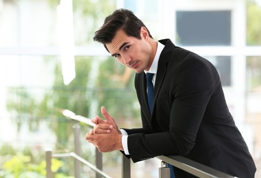 Handsome young man in stylish suit indoors. Space for text