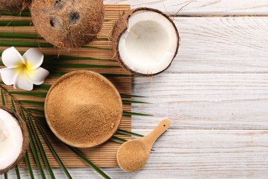 Photo of Coconut sugar, palm leaves, fruits and bamboo mat on wooden rustic table, flat lay. Space for text