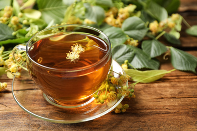 Photo of Cup of tea and linden blossom on wooden table