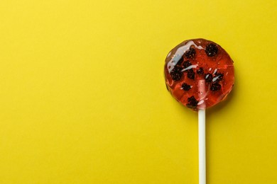 Photo of Sweet colorful lollipop with berries on yellow background, top view. Space for text