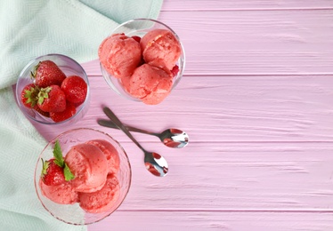 Photo of Flat lay composition with delicious strawberry ice cream on pink wooden table, space for text