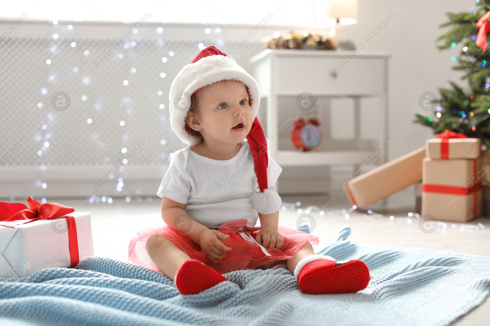 Photo of Cute baby in Christmas costume on floor at home