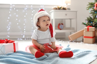 Cute baby in Christmas costume on floor at home