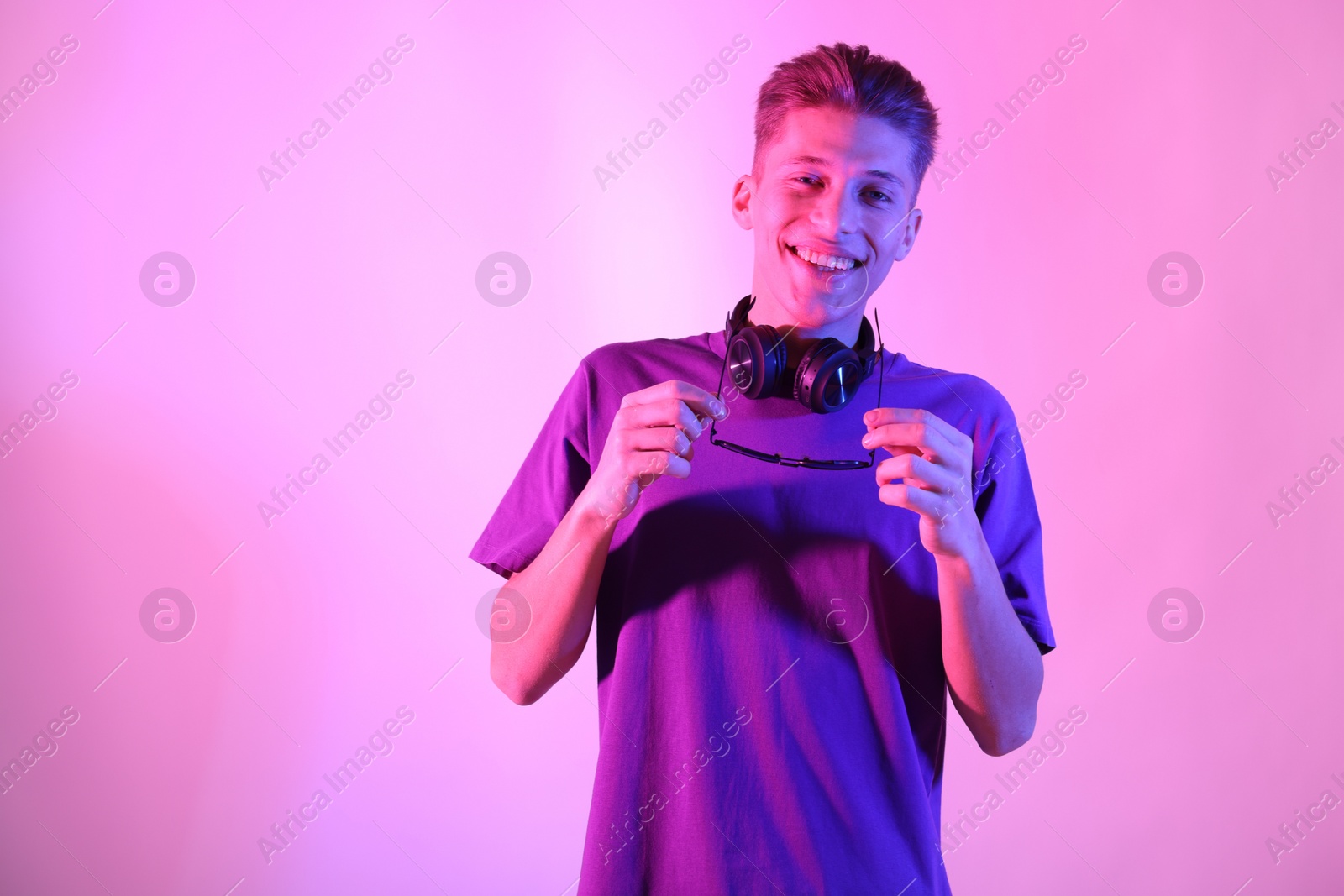 Photo of Young man with sunglasses on pink background in neon lights