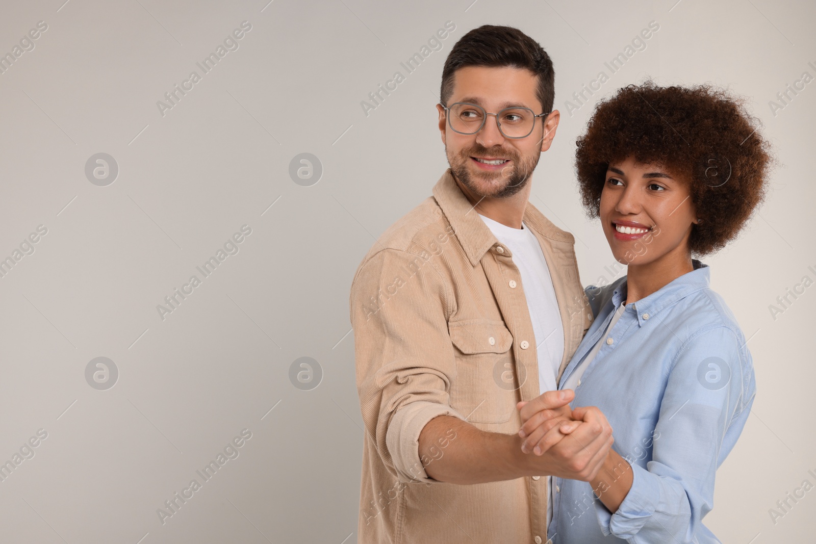 Photo of International dating. Happy couple dancing on light grey background, space for text