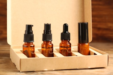 Photo of Bottles with oil in box on wooden table, closeup. Natural cosmetics