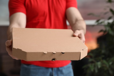 Courier with pizza box on blurred background, closeup. Space for text